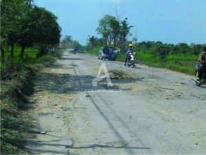RUSAK. Beberapa kendaraan sedang melintas di ruas jalan yang rusak parah. Kerusakan jalan tersebut dipicu oleh kendaraan yang bermuatan melebihi tonase.