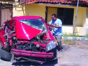 RINGSEK. Salah satu keluarga sopir mobil sedan melihat kondisi kendaraan sedan di halaman Polsek Kota Sampang pasca terjadi kecelakaan, Selasa (23/6).