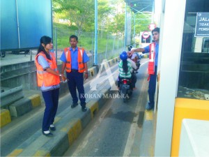 BERDIRI. Petugas saat berjaga di sekitar loket untuk mengarahkan pengendara Roda 2 yang akan melintas. Sejak Sabtu (13/6) lalu, pemerintah menggratiskan kendaraan roda 2 yang melewati tol jembatan Suramadu. Dengan diberlakukannya penggratisan tersebut, pendapatan yang dihasilkan Rp 3 miliar per bulan hilang.