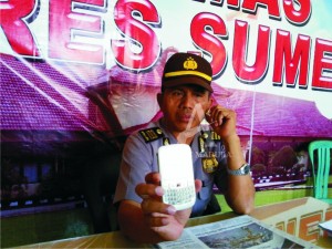 TUNJUKKAN. Kasubag Humas Polres Sumenep AKP Hasanuddin memperlihatkan barang bukti melalui telepon selulenya, Selasa (8/9).