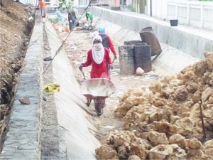 DIKERJAKAN. Sejumah pekerja sedang mengerjakan proyek perbaikan sungai atau turap di kelurahan Bagandan, Kecamatan kota, Pamekasan.