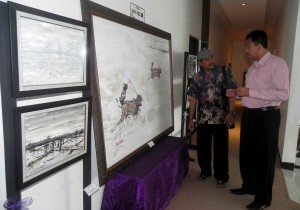 PAMERAN. Budi Hariyanto (kiri) sedang menjelaskan kepada salah seorang tamu hotel, yang melihat karya lukisannya, Kamis (4/8).